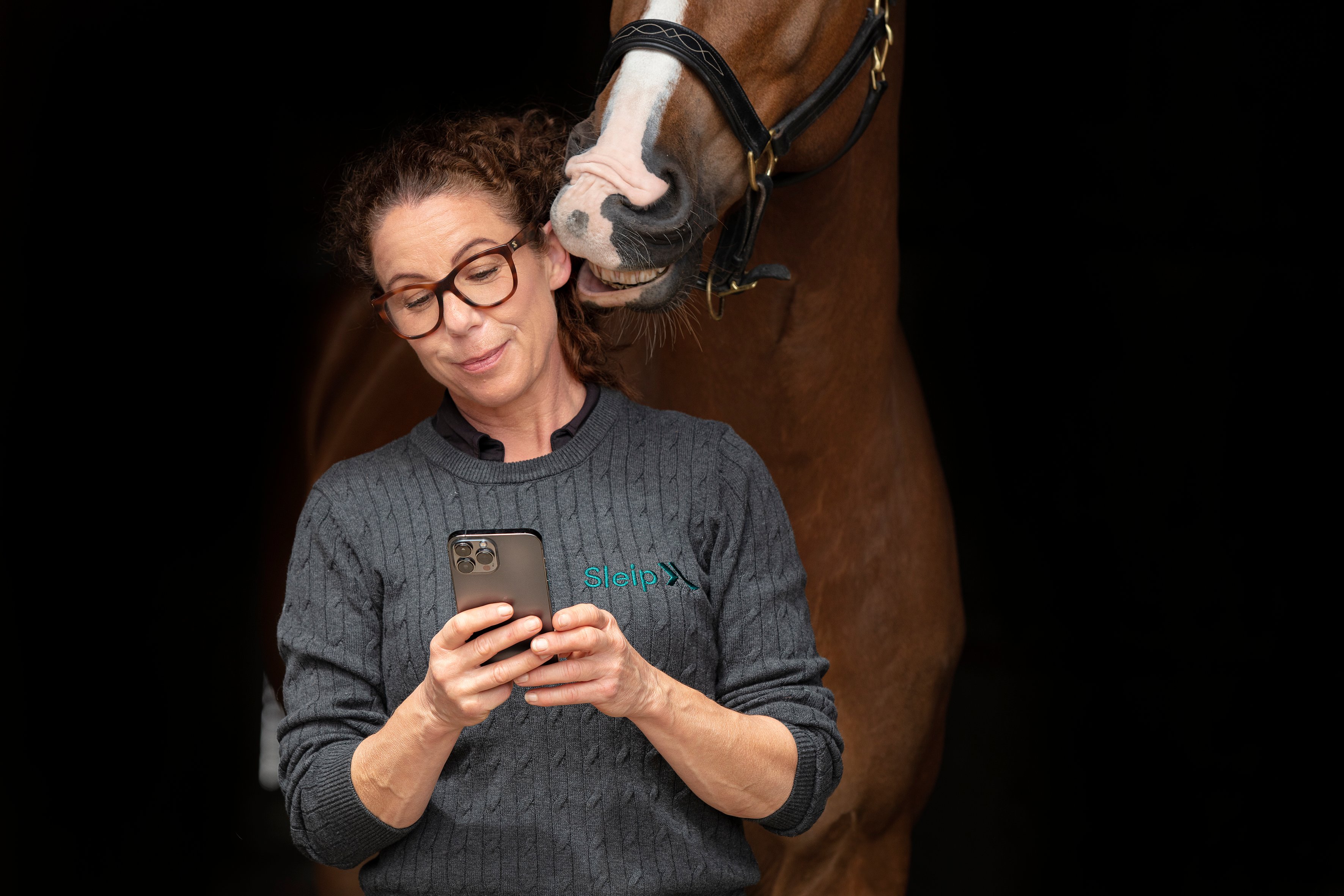 the woman in front of the horse, holding an iPhone
